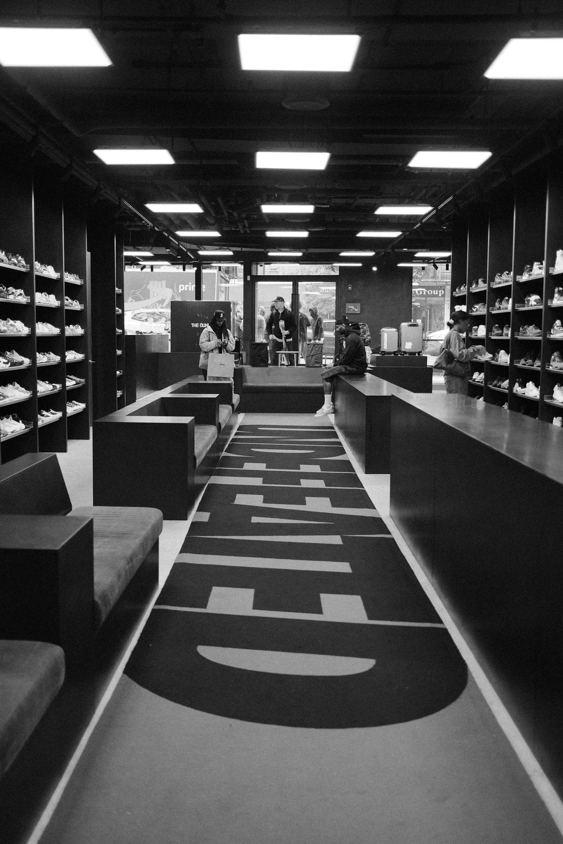 Tienda de calzado con estantes iluminados y bancos para probar producto.